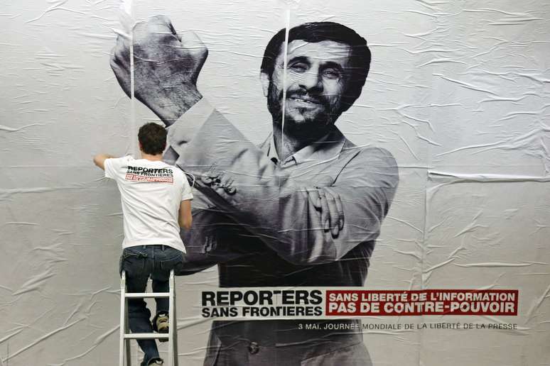 Ativista cola cartaz com a imagem do presidente do Irã, Mahmoud Ahmadinejad, mandando "uma banana", na estação de metro Opera, em Paris