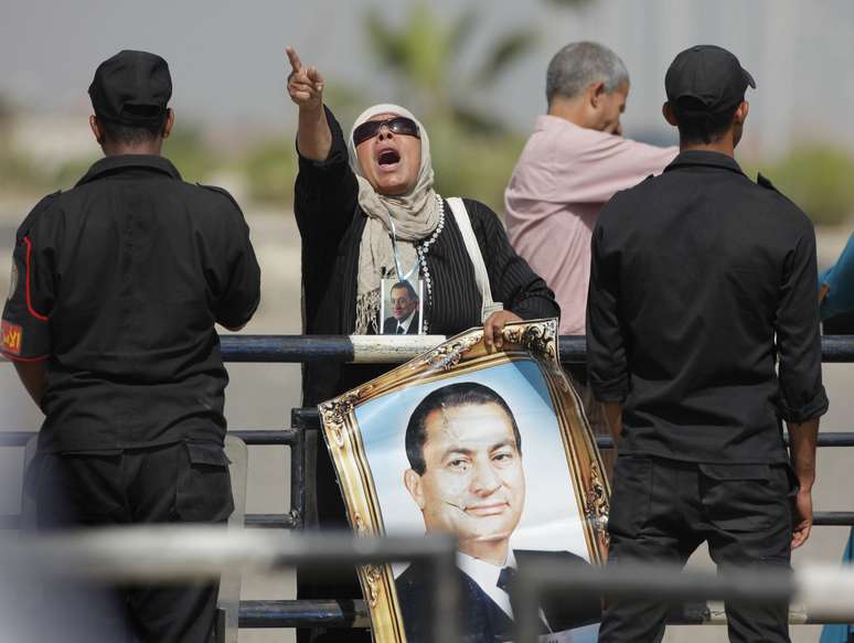 Do lado de fora da polícia, onde ocorre julgamento, apoiadores de Mubarak exibiam cartazes e gritavam slogans