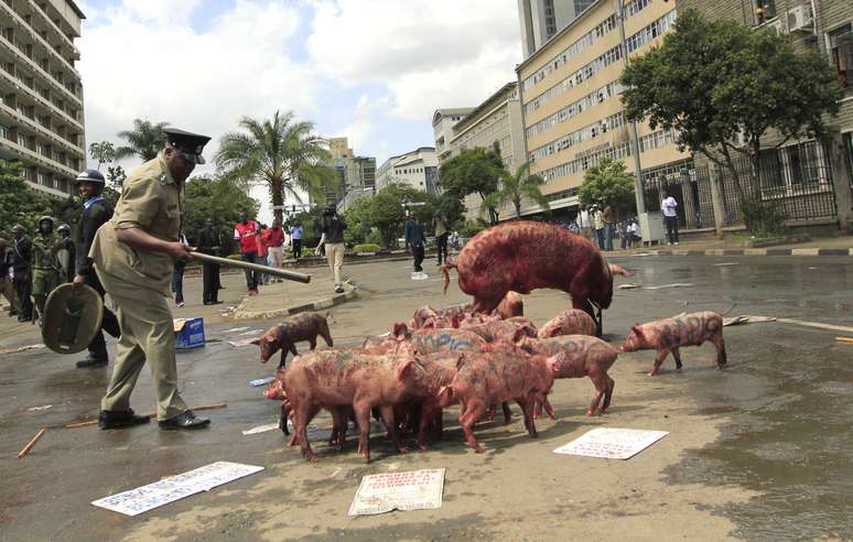 <p>Policial observa porcos deixados por manifestantes em frente ao Parlamento</p>
