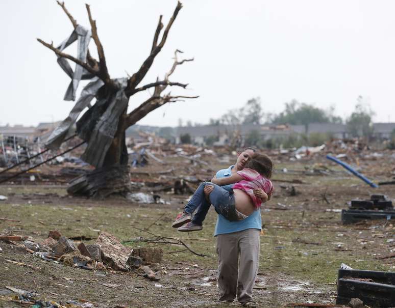 <p>Mulher carrega criança em meio aos destroços da passagem do tornado em Moore, no subúrbio da Cidade de Oklahoma</p>