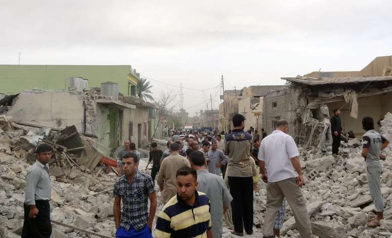 Residentes vagam por escombros após os ataques em Tuz Khormatu, no norte do Iraque