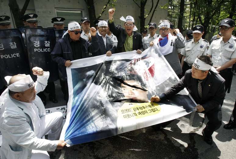 Manifestantes sul-coreanos usam faca para rasgar retrato de Hashimoto durante protesto em Seul nesta terça-feira