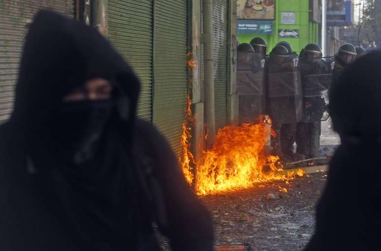 Manifestantes encapuzados são vistos durante confronto com a polícia na terça-feira, em Valparaíso