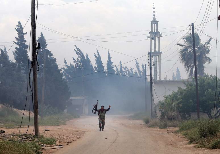 <p><strong>13 de maio</strong> - Soldado do Exército sírio caminha após tomada do controle da vila de Dumayna Ocidental, a sete quilômetros da Qusair</p>