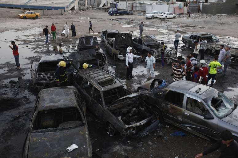 <p>Moradores observam carros destru&iacute;dos em explos&otilde;es em Bagd&aacute; na segunda-feira</p>