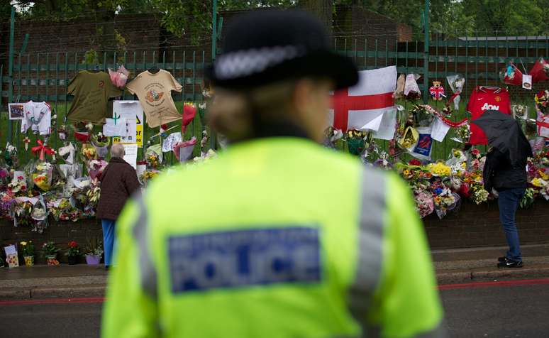 Policial observa homenagens ao soldado morto em um ataque em Woowich, Londres
