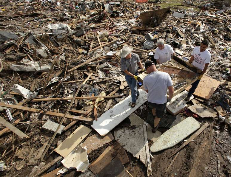 Familiares e amigos carregam resto de piano encontrado nos escombros de uma casa destruída em Moore