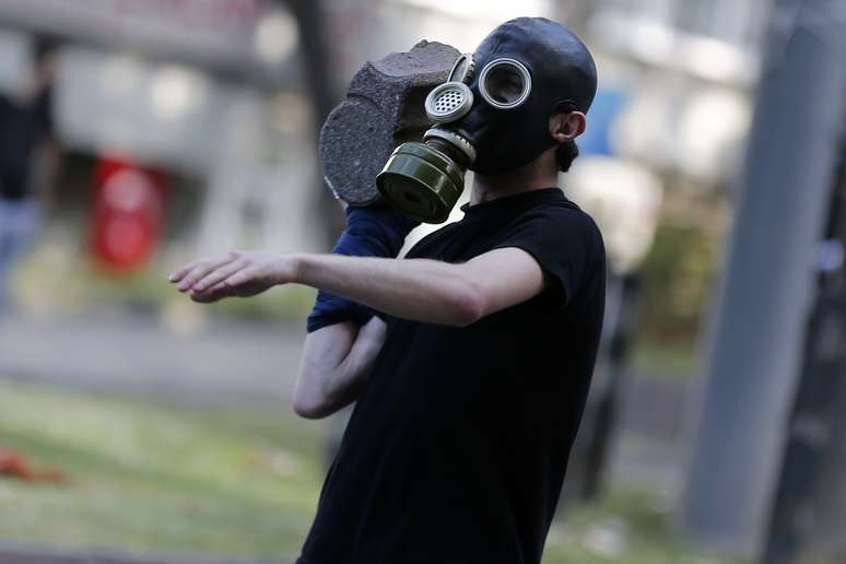 <p>Homem se prepara para atirar uma pedra na polícia de choque</p>