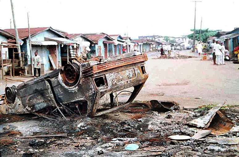 Carro destruído em distrito de Lagos em meio aos conflitos durante o retorno do governo civil em 1999