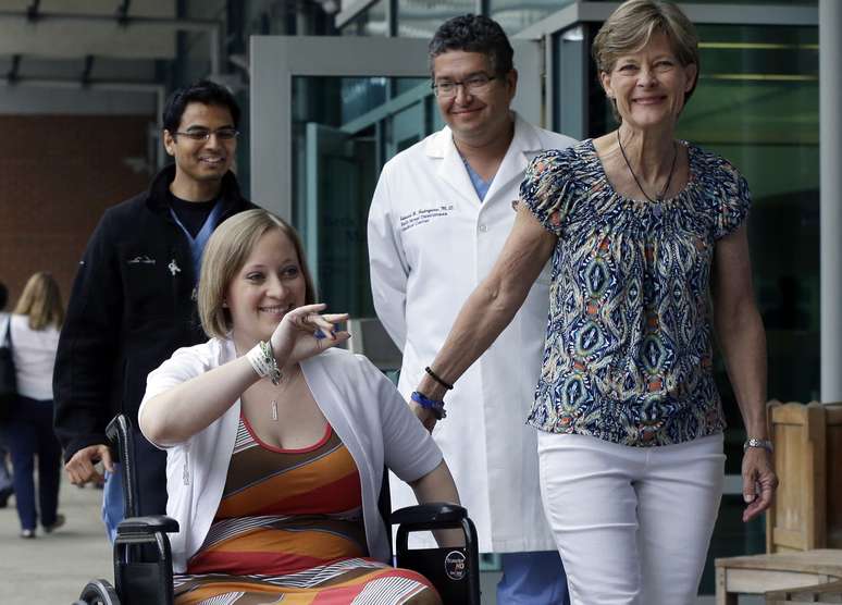 Erika é acompanhada pela mãe, Carol Downing (dir.), e por médicos ao deixar o hospital