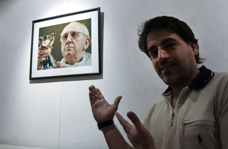 O fotógrafo argentino Miguel Cangas ao lado de uma das imagens da exposição 