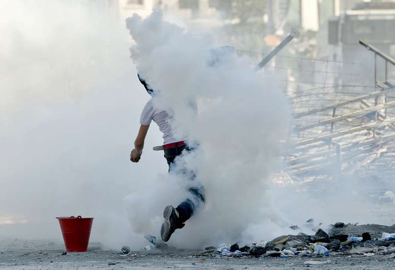 11 de junho - Manifestante atira bomba de g&aacute;s de volta durante novos confronto com policiais na Pra&ccedil;a Taksim, em Istambul
