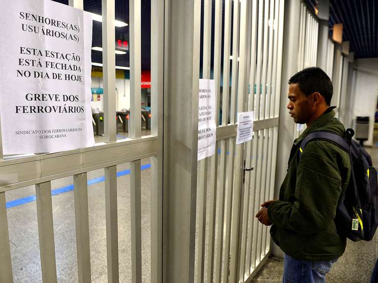 Homem observa cartazes avisando sobre a greve dos ferroviários na estação Grajaú, em São Paulo