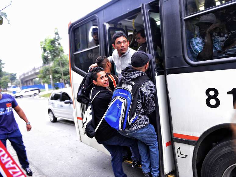 Homens se arriscam e pegam ônibus pendurados na porta traseira