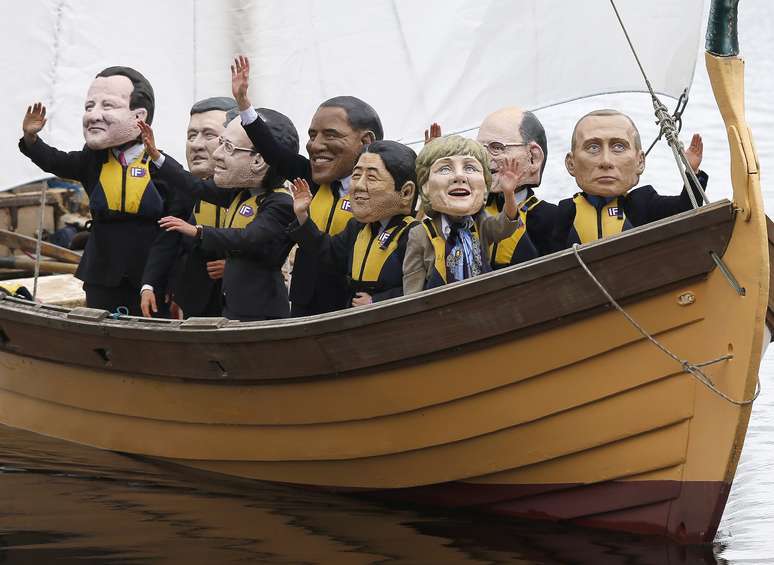 <p>Manifestantes usando máscaras dos líderes do G8 chegam a bordo de uma réplica de um barco viking</p>