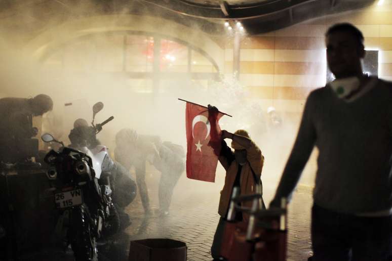 Manifestantes buscam proteção em meio à fumaça durante os confrontos na praça Taksim