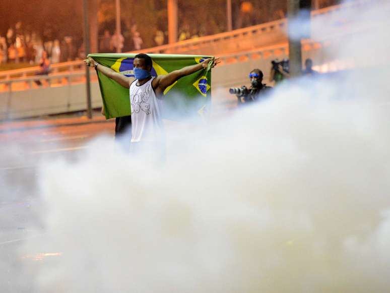 <p>Manifestante em meio à fumaça de bombas de efeito moral disparadas por PMs</p>