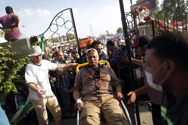 Homem ferido é transferido de cadeiras de rodas a hospital improvisado após o massacre