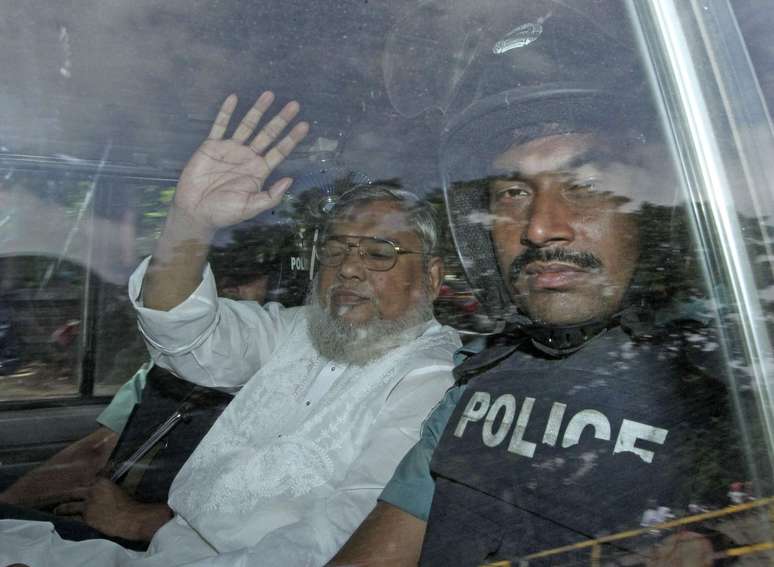 Ali Ahsan Mohammad Mojaheed acena ao entrar em tribunal de Daca nesta quarta-feira