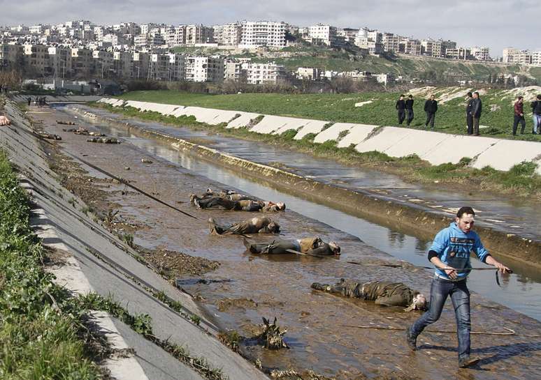 Homem passa por corpos ao lado de rio em Aleppo, em 29 de janeiro de 2013