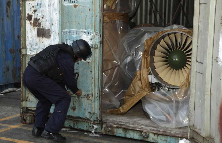 Policial abre um contêiner onde foi encontrado motor de fabricação russa