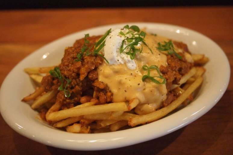 A batata é um acompanhamento recorrente, mas vem em diferentes versões: chips, brava, rústica, assada, palito com queijo e bacon ou, como na foto, com chili e queijo. A porção é do Buchers Market