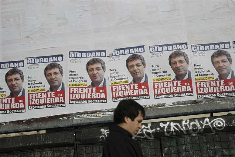 Homem passa em frente a cartazes eleitorais em uma rua de Buenos Aires neste sábado