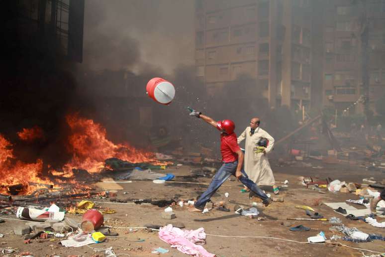Manifestante joga galão d'água em fogo para tentar conter incêndio provocado pelos confrontos no Cairo
