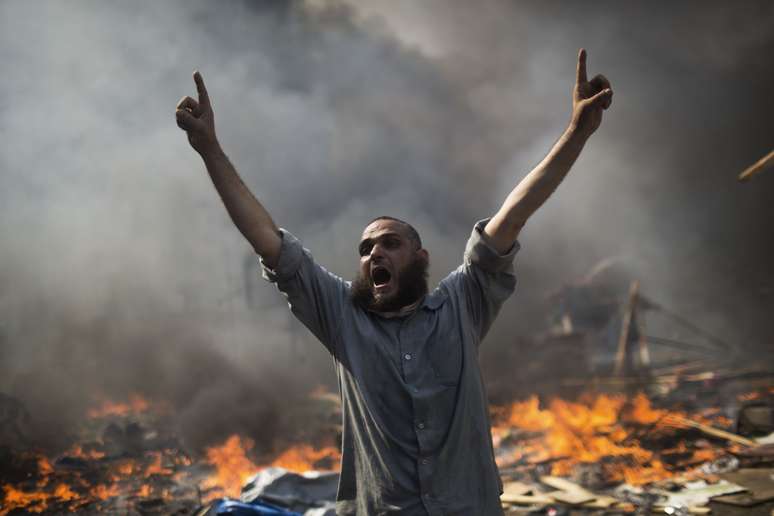 Manifestante partidário de Mohamed Mursi reage em meio às chamas e aos confrontos com as forças de segurança do Egito na Cidade Nasser, no Cairo