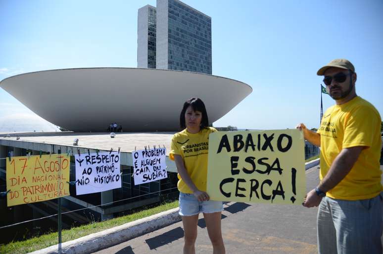 <p>Os arquitetos Leiliane Rebou&ccedil;as e Cristiano Nascimento protestam&nbsp;com cartazes</p>