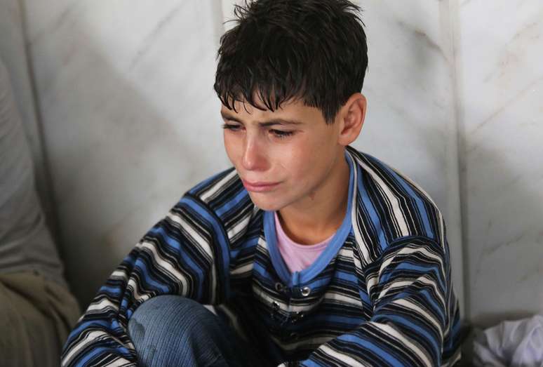 Menino chora após o ataque que, segundo a oposição, deixou centenas de mortos em Damasco