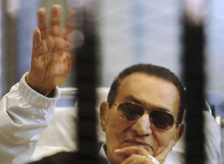 <p>Ex-presidente egípcio Hosni Mubarak acena para seus apoiadores de dentro de uma cela em uma corte de uma academia de polícia</p>