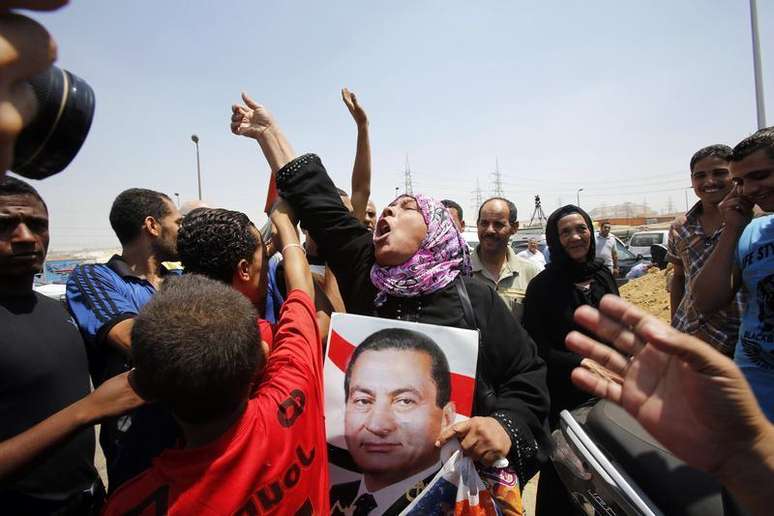 Simpatizante do ex-presidente do Egito Hosni Mubarak segura um cartaz dele para comemorar sua libertação, enquanto espera a saída dele em frente ao portal principal da prisão Tora, nos arredores do Cairo. Mubarak pode deixar a prisão nesta quinta-feira por ordem judicial, após uma semana violenta no país em que os novos governantes apoiados pelo Exército reprimiram a Irmandade Muçulmana, do presidente deposto Mohamed Mursi. 22/08/2013.