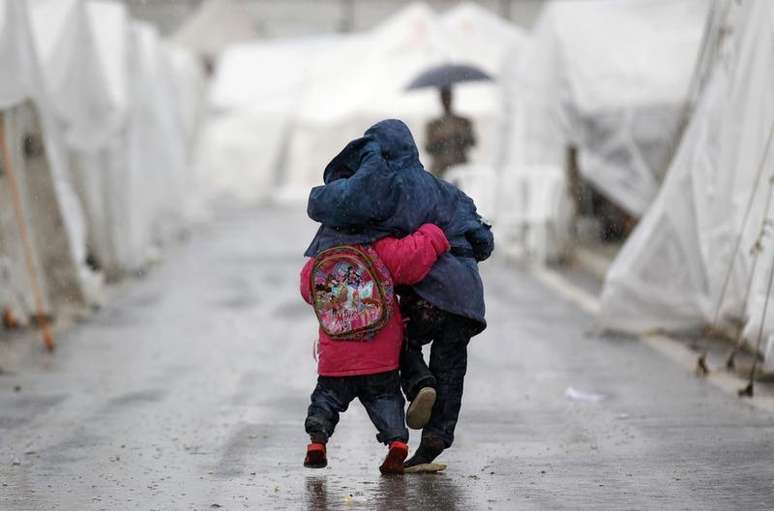 <p>Crian&ccedil;as s&iacute;rias caminham sob a chuva no campo de refugiados de Boynuyogun, na fronteira entre a S&iacute;ria e Turquia</p>