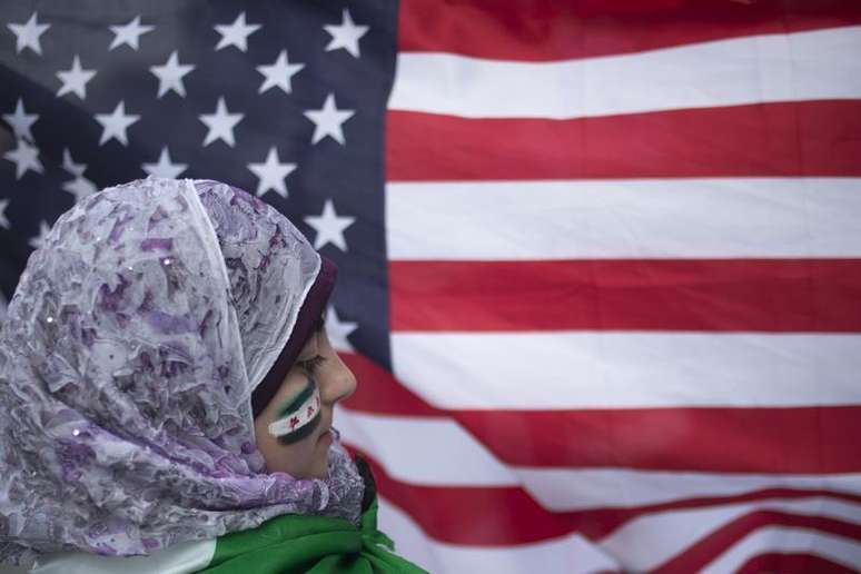 <p>Garota síria Malek Al Rifai fica perto da bandeira dos Estados Unidos enquanto participa de um protesto em frente ao prédio das Nações Unidas, em Nova York</p>