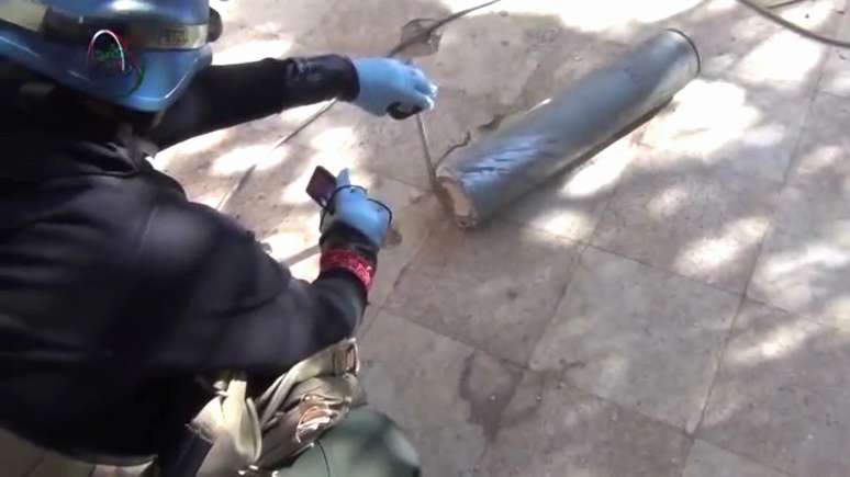 Membro da equipe de investigação da ONU fotografa cápsula metálica durante visita à periferia de Damasco