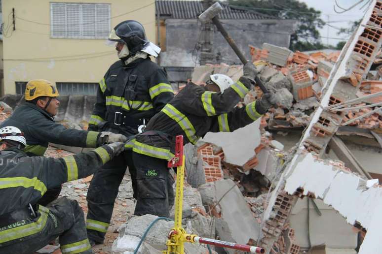 <p>Militares seguram companheiro pela roupa, durante remoção de escombros</p>