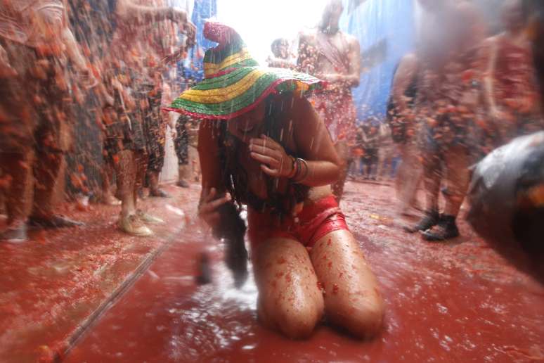 <p>Jovem se ajoelha em poça de suco de tomate durante a festa anual da "Tomatina" na cidade de Buñol, na Espanha. De acordo o governo local, cerca de 20 mil pessoas se reuniram nas ruas da cidade para participar da "guerra" de tomates nesta quarta-feira. Para participar é preciso pagar 10 euros - moradores locais são isentos -, utilizados para cobrir os custos do festival. Segundo a AFP, 130 toneladas de tomate são utilizadas. A festa é realizada desde os anos 1940 e tem inspiração em brigas de comida de crianças</p>