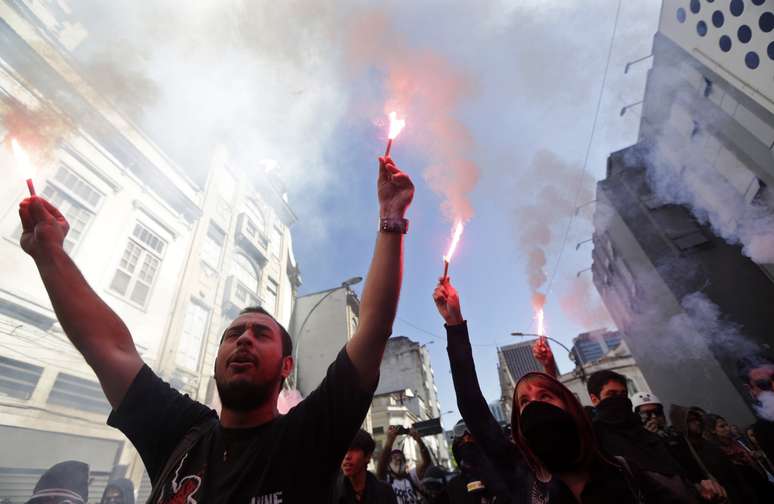 Manifestantes seguram sinalizadores durante protesto