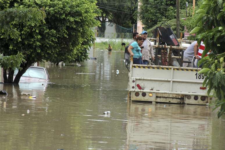 População afetada pela enchente viaja na parte de trás de um caminhão através de um bairro inundado em Poza Rica