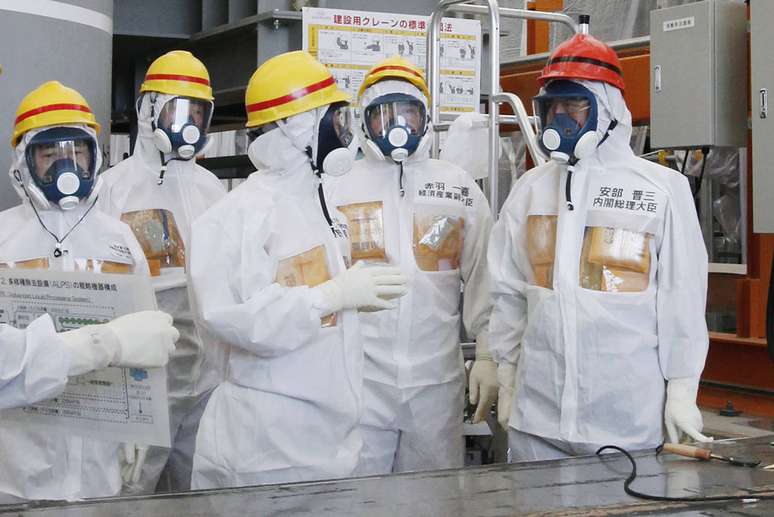 Shinzo Abe (dir.) veste traje protetivo durante visita à usina nuclear