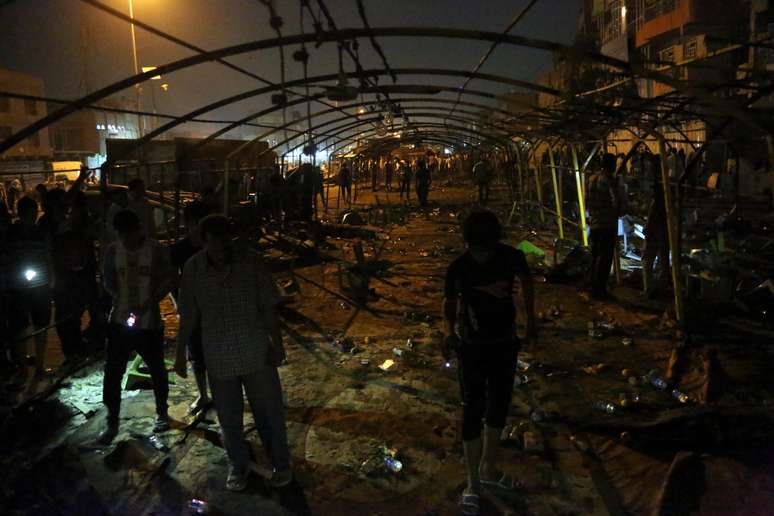 Civis caminham por local de atentado que deixou dezenas de mortos em reduto xiita de Bagdá