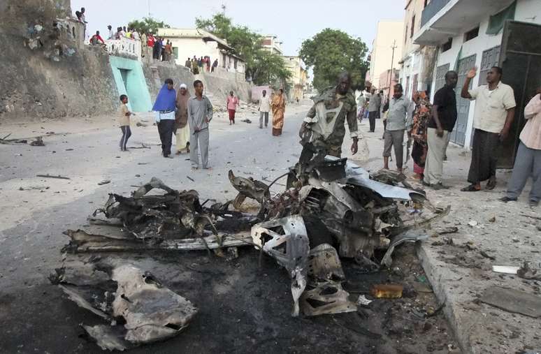 Somalis observam o que restou de veículo usado como carro-bomba em Mogadíscio em 8 de fevereiro de 2012
