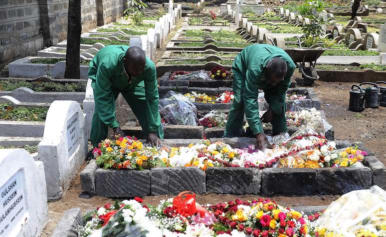 Funcionários de um cemitério da capital do Quênia colocam flores em uma das sepulturas