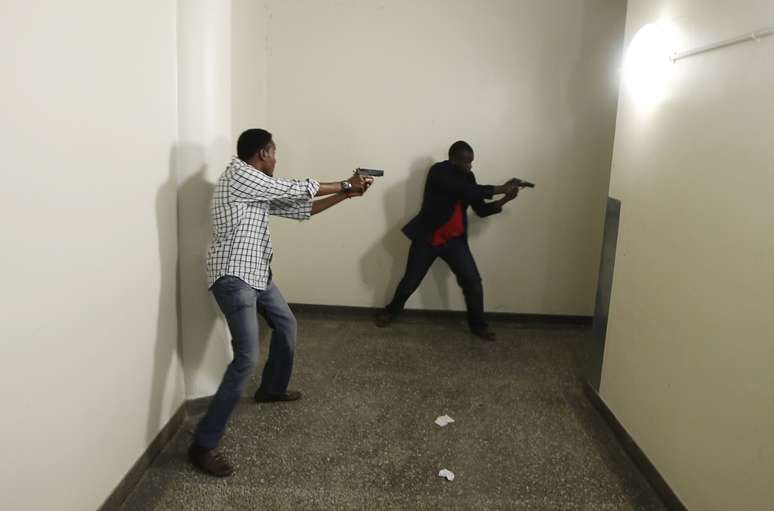 <p>Abdul Haji (esq.) com uma arma na mão procura por sobreviventes no Westgate no sábado</p>
