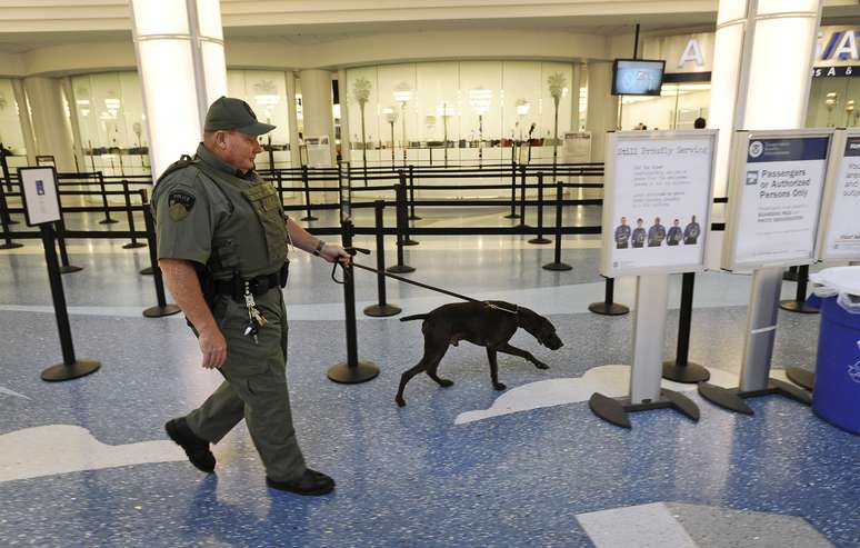 Policial vistoria terminal do aeroporto de Jacksonville com cão farejador