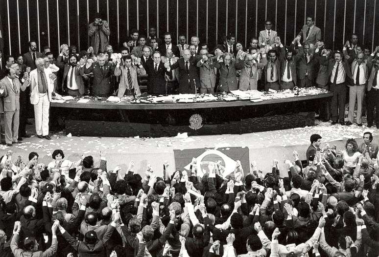 Membros da Constituinte dão as mãos durante a execução do Hino Nacional