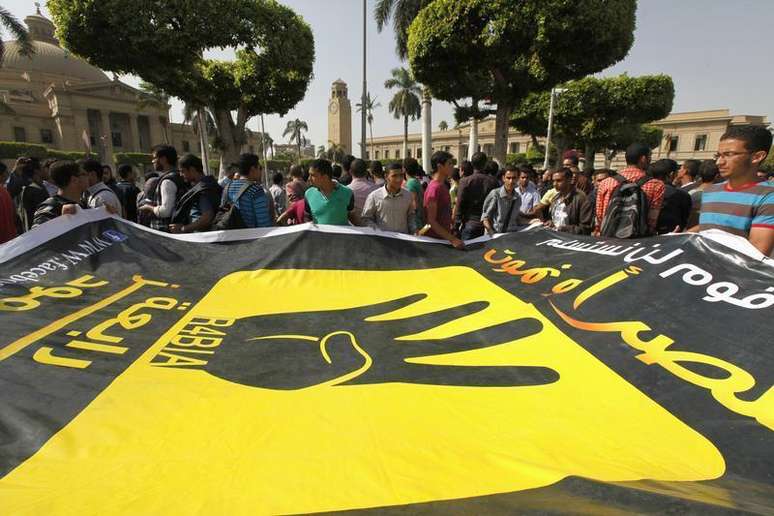 Estudantes da Universidade do Cairo e membros da Irmandade Muçulmana carregam um banner com o símbolo dos quatro dedos de Rabaa, durante protesto contra os militares em frente à Universidade do Cairo. Centenas de seguidores da Irmandade Muçulmana protestaram nesta terça-feira gritando "abaixo o governo militar" diante da Universidade do Cairo, num desafio às autoridades egípcias apoiadas pelo Exército, apesar dos confrontos com forças de segurança ocorridos há dois dias. 8/10/2013.