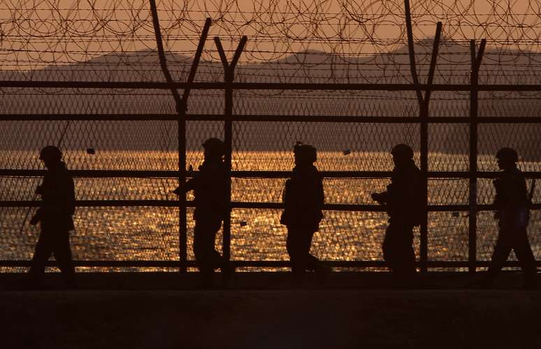 <p>Soldados fazem guarda na Zona Desmilitarizada (DMZ); ao fundo, o relevo da cidade de Paju, na Coreia do Sul</p>