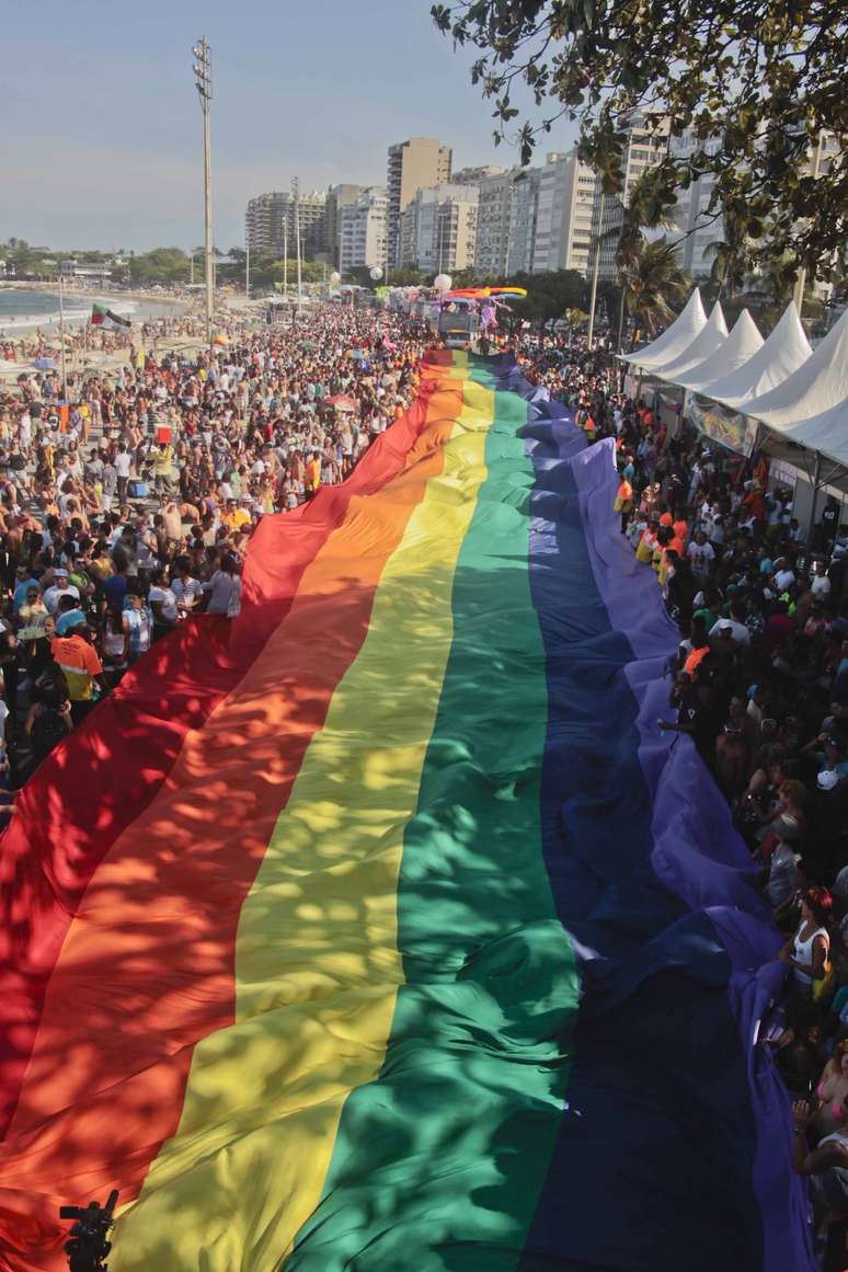 Público segura uma imensa bandeira com as cores do arco-íris durante a 18ª Parada LGBT